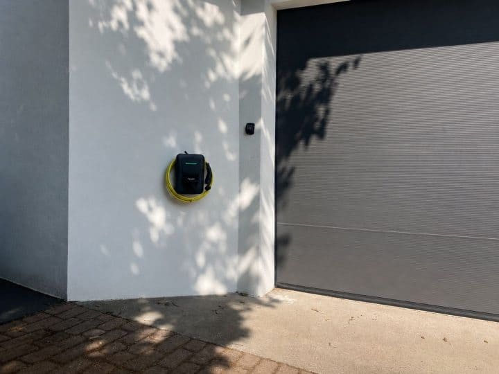 Wallbox mit Ladekabel neben moderner Garage